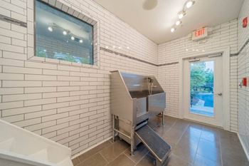 a white tiled bathroom with a sink and a refrigerator